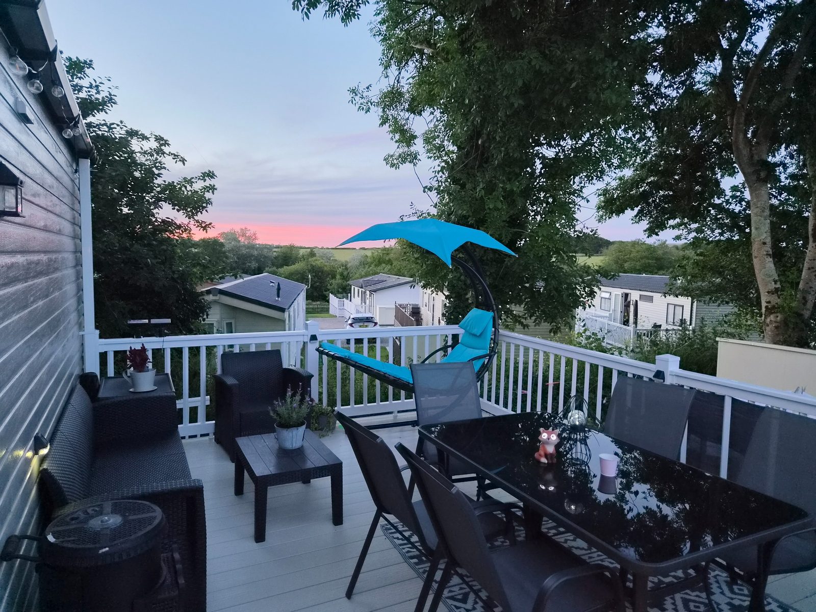 Private decking with outdoor seating and countryside views at sunset.