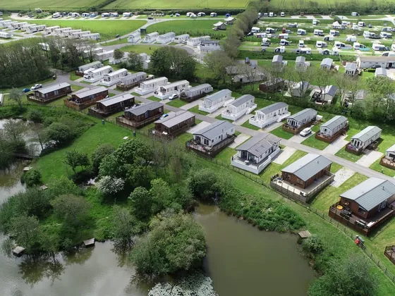 Aerial view of the holiday park with caravans, lakes and green surroundings.