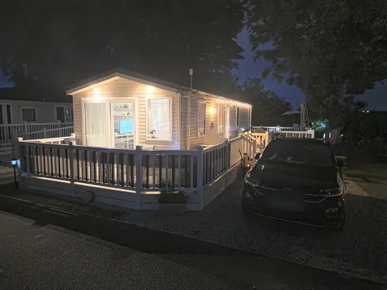 Fox Hole Retreat lit up at night with decking lights.