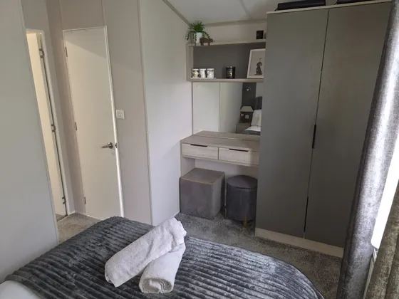 King-size main bedroom with wardrobe, dressing table, soft grey styling and en-suite toilet facilities.