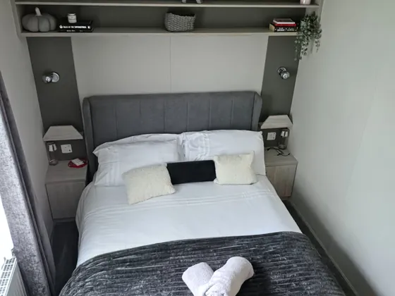 Freshly made king-size main bedroom with soft furnishings and bedside storage.